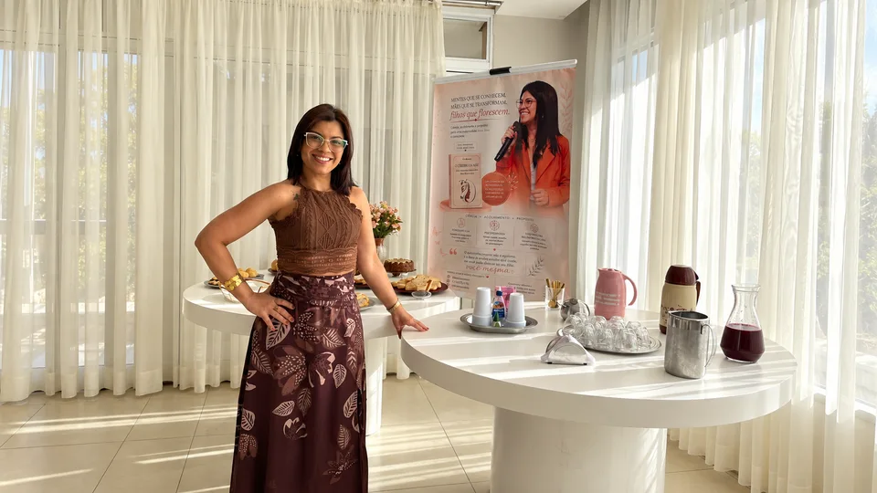 Ana ao lado da mesa e do painel do encontro